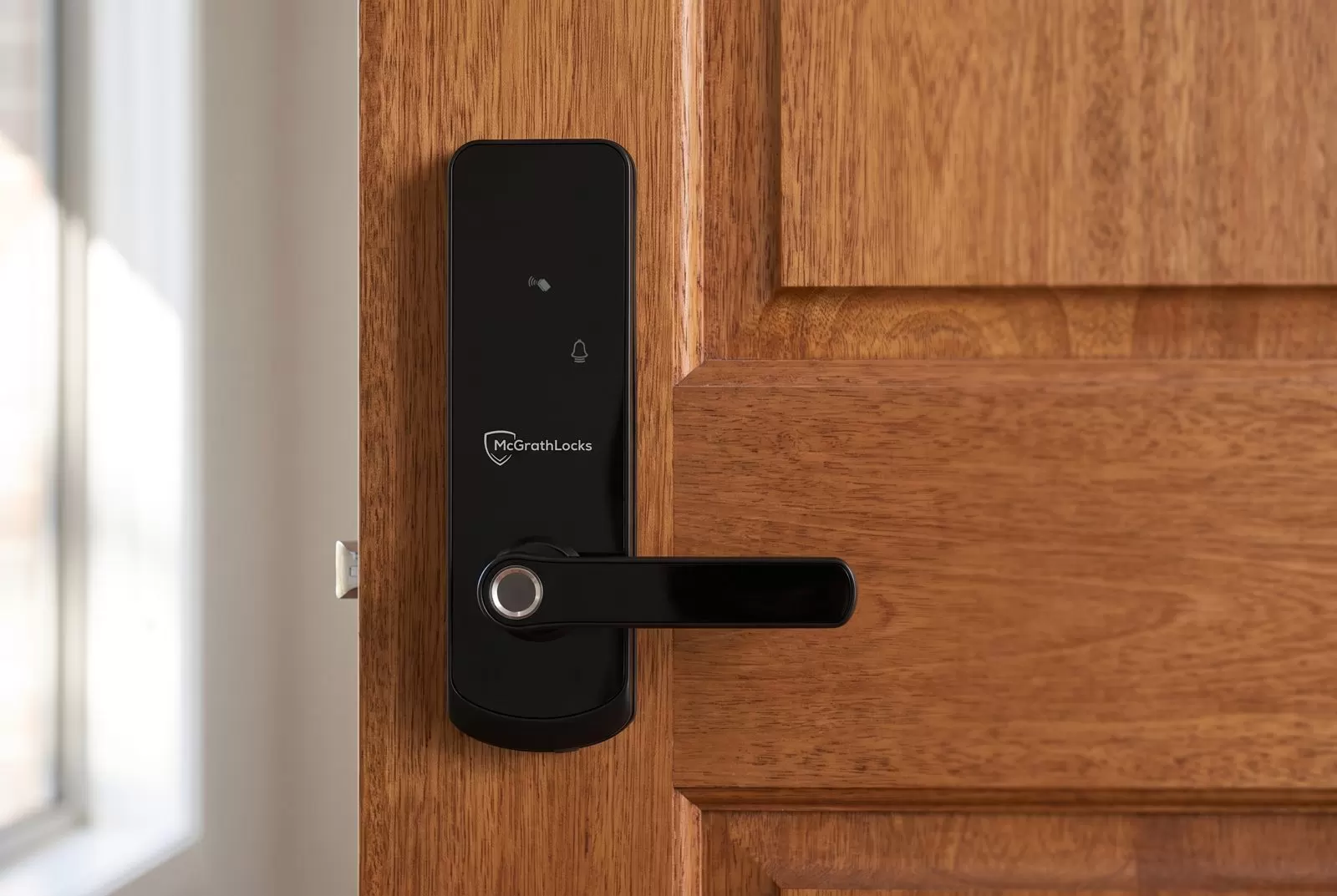 A black McGrath NX1 digital lock with a fingerprint reader fitted to a solid timber front door